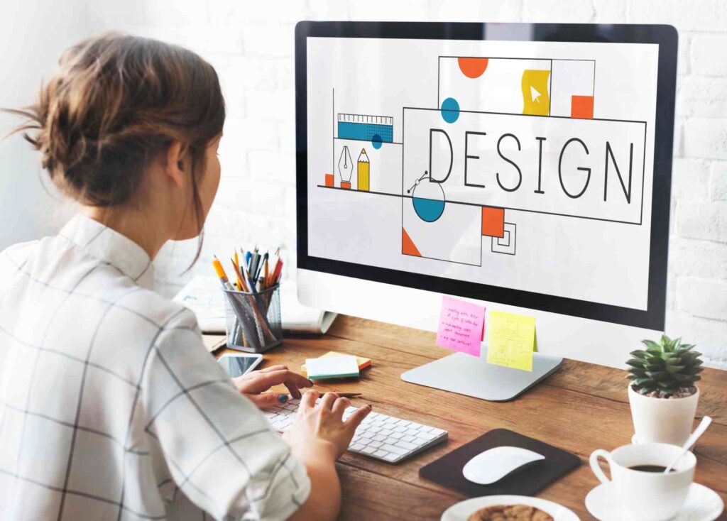Frau sitzt an einem Schreibtisch und gestaltet am Computer ein modernes Webdesign mit Fokus auf Farben und Kontraste. Das Bild symbolisiert barrierefreies Design und visuelle Lesbarkeit für inklusive digitale Inhalte