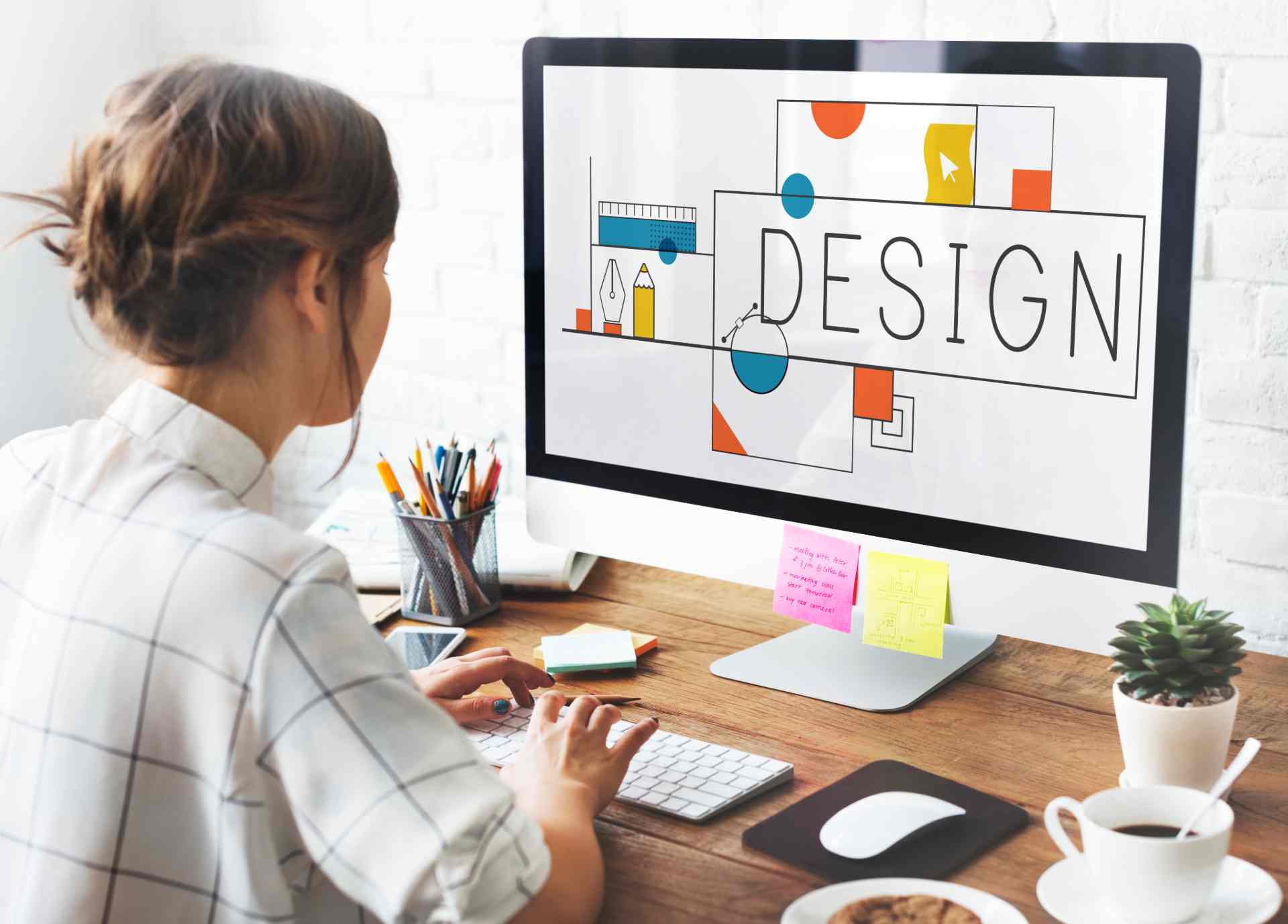 Frau sitzt an einem Schreibtisch und gestaltet am Computer ein modernes Webdesign mit Fokus auf Farben und Kontraste. Das Bild symbolisiert barrierefreies Design und visuelle Lesbarkeit für inklusive digitale Inhalte